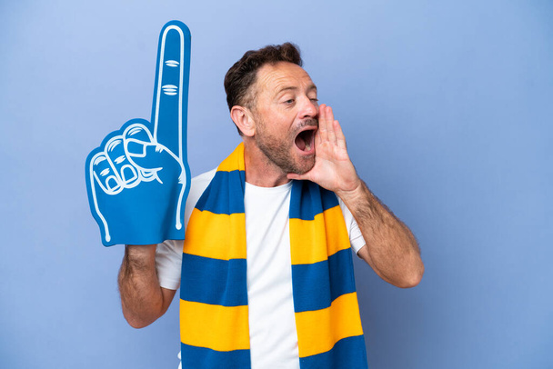 Ventilador de esportes caucasiano de meia idade homem isolado no fundo azul gritando com a boca bem aberta para o lado - Foto, Imagem