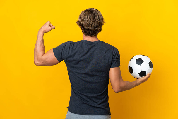 İngiliz adam futbol topuyla izole edilmiş sarı arka plan - Fotoğraf, Görsel