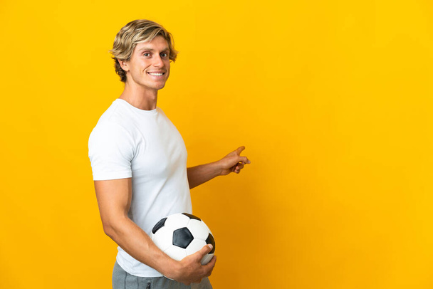 English football player over isolated yellow background pointing back - Valokuva, kuva