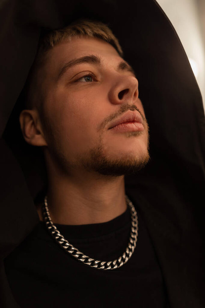 Headshot of a young handsome fashionable guy wearing a trendy black hoodie. Fashion man in black clothes - Zdjęcie, obraz