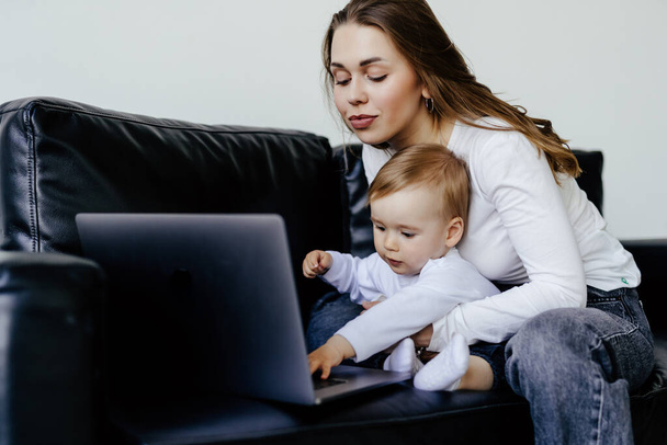freelancer sorrindo apontando para laptop enquanto segurando pequeno filho - Foto, Imagem