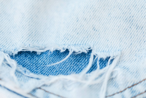 Blauwe denim stof textuur. close-up. Fashion gescheurde jeans - Foto, afbeelding