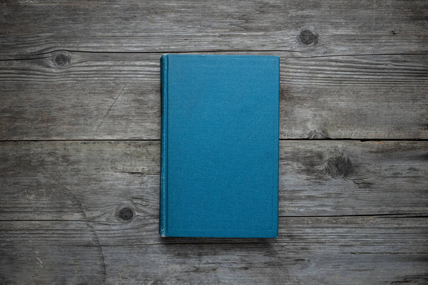 A closed book on an old wooden table. Blue hard cover. Vintage background. - Foto, Imagem