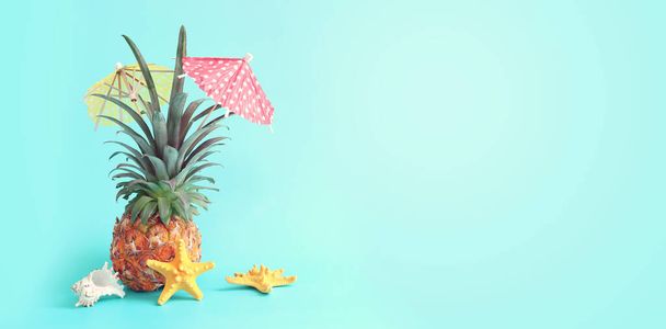 Image with ripe pineapple with parasol over blue background. Summer holidays and tropical theme - Фото, изображение