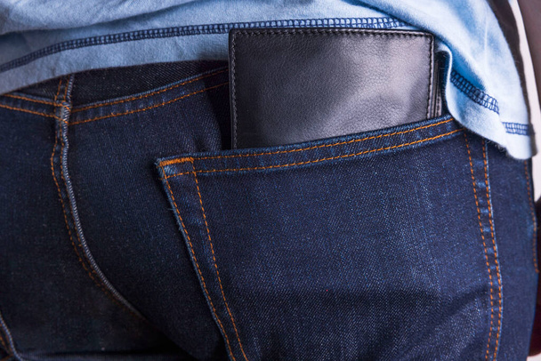 Close up widok brązowy skórzany portfel w dżinsach tylnej kieszeni.  - Zdjęcie, obraz