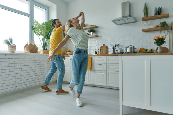 Full length of playful couple dancing at the domestic kitchen - Φωτογραφία, εικόνα