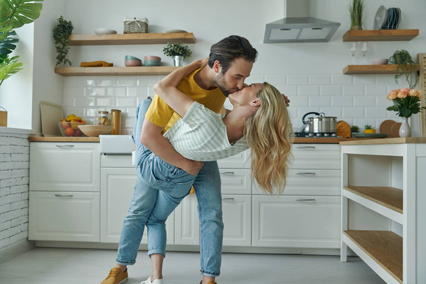 Beautiful young loving couple dancing and kissing at the domestic kitchen - Fotoğraf, Görsel
