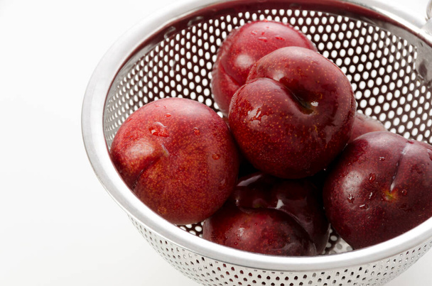 Japanese plum (Prunus salicina)  in a stainless steel colander on white background - Photo, Image