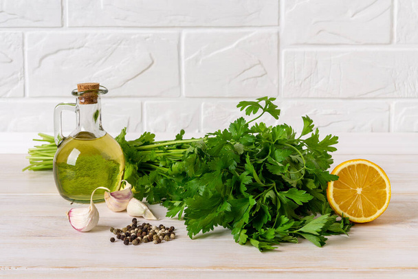 Green sauce ingredients. Salsa verde from fresh parsley, garlic cloves, olive oil and lemon juice. Homemade chimichurri dipping sauce with fresh herb and spices. Cooking healthy condiment. Front view. - Фото, изображение