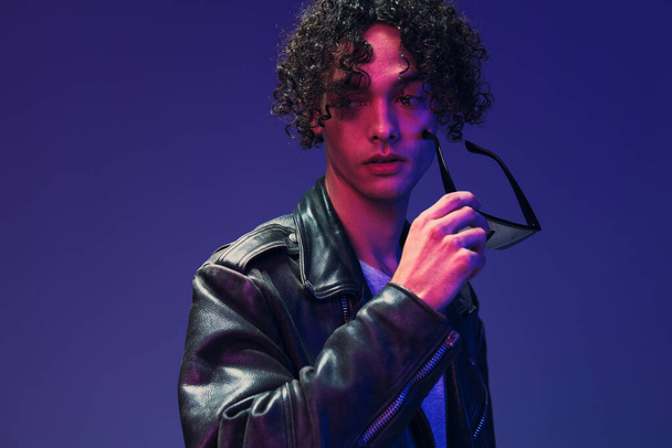 Cyberpunk style curly man leather jacket mirror eyewear looks aside posing isolated on color pink blue studio background. Cool fashion offer. Huge Seasonal Sale New Collection concept. Copy space ad - Photo, Image