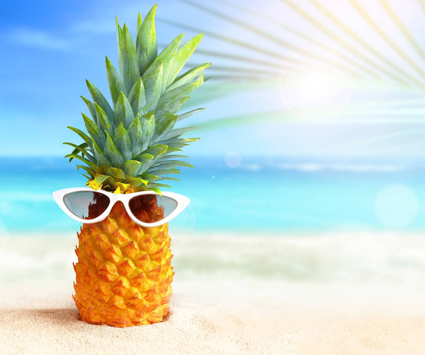Ananas mit Sonnenbrille vor tropischem Strand-Hintergrund. Sommerkonzept. - Foto, Bild