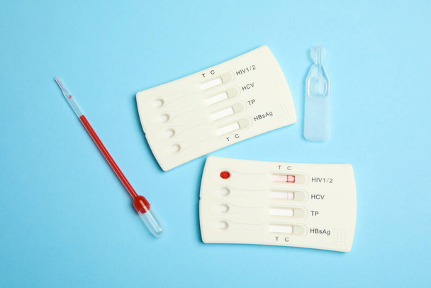 Disposable express hepatitis test kit on light blue background, flat lay - Foto, afbeelding