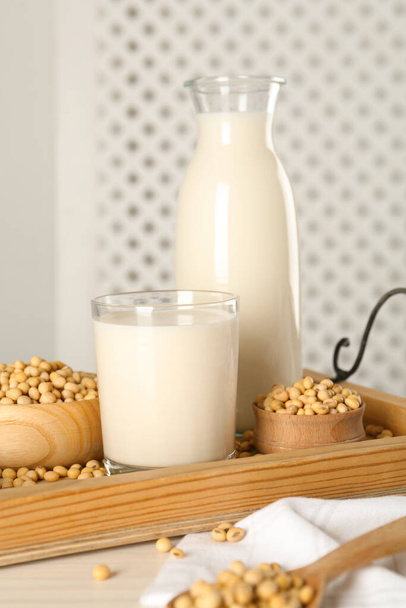 Fresh soy milk and beans on wooden table, closeup - Foto, afbeelding