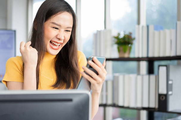 Portrait jeune programmeuse heureuse femme asiatique travaillent au bureau de technologie de démarrage et à l'aide de smartphone et de tester l'application mobile et excité dans le succès. Concept de femme entrepreneure intelligente travaillant. - Photo, image