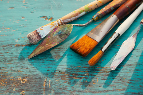 Artistic art supply utensils with paintbrushes on turquoise wooden background with copy space.  - Fotoğraf, Görsel