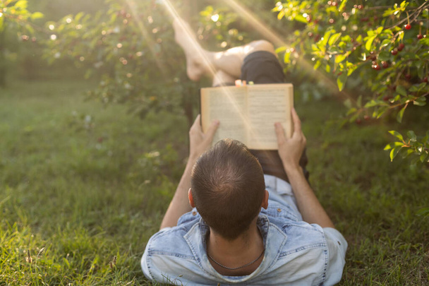ember Olvasson egy könyvet a fűben. - Fotó, kép