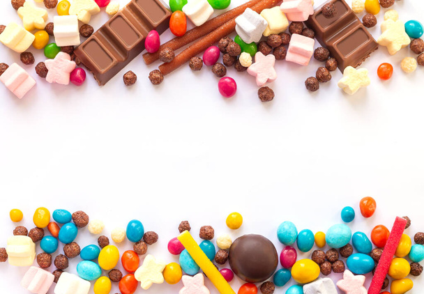 Colorida mezcla de caramelos de frutas y bombones de chocolate aislados sobre fondo blanco. Vista superior - Foto, imagen