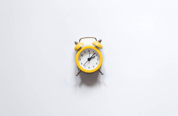 Yellow alarm clock on white background isolated, flat lay, time concept, conceptual minimalism. - Valokuva, kuva