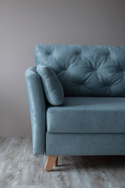 Beautiful vintage blue sofa stands on the wooden floor near the beige wall in the living room. A relaxing and comfortable sofa. Stylish interior - Valokuva, kuva
