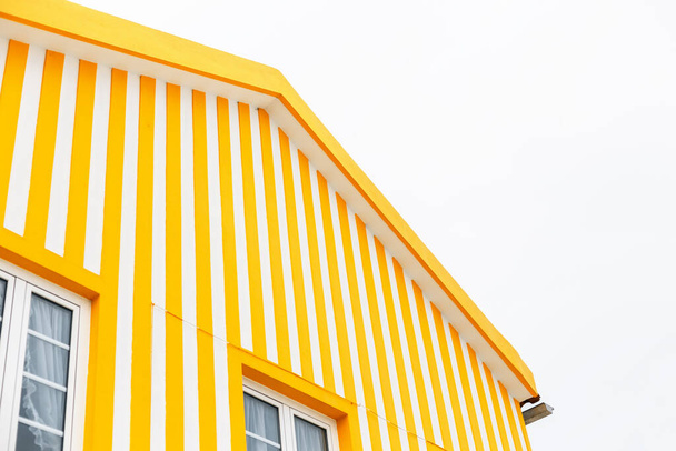 Casa creativa de colores brillantes con rayas blancas y amarillas en la playa de Portugal. Paredes de apartamentos de colores brillantes. Minimalismo de color, concepto - Foto, Imagen
