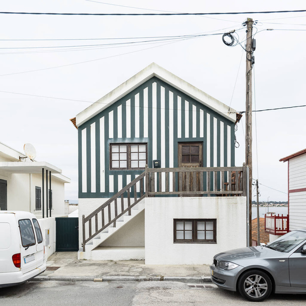 Beautiful vintage wooden striped house near a road with cars in Portugal. Beautiful fishing village with creative architecture. Vacation by the sea - Foto, imagen