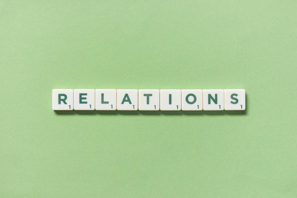 Relations word formed of scrabble blocks on green background, still life with copy space. - Photo, Image