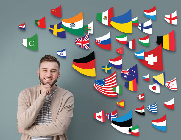 Portrait of interpreter and flags of different countries on grey background - Photo, Image
