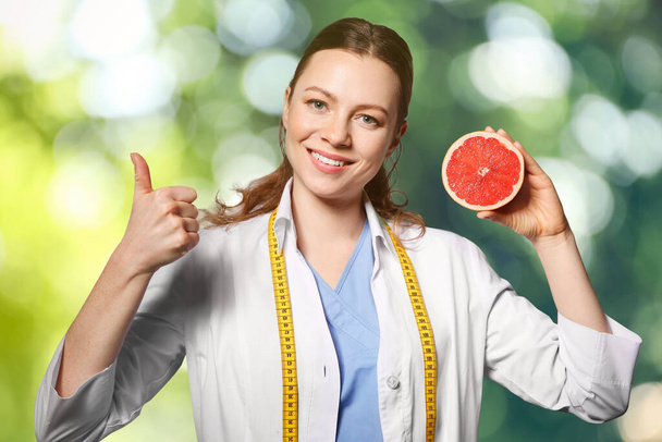 Nutritionist with grapefruit on blurred green background - 写真・画像