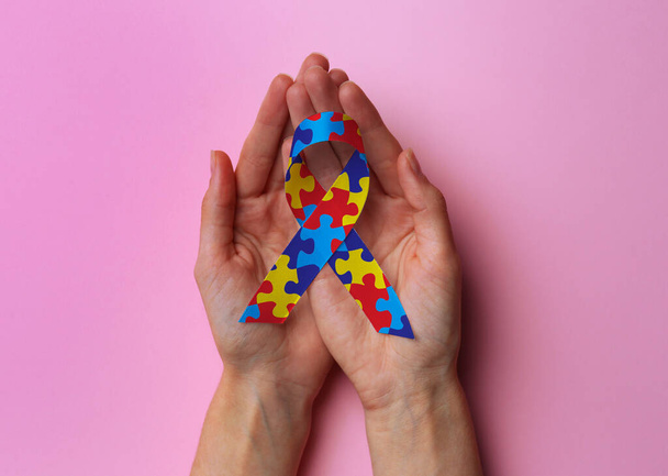World Autism Awareness Day. Woman with colorful puzzle ribbon on pink background, top view - Foto, immagini
