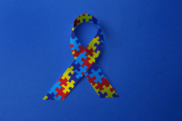 World Autism Awareness Day. Colorful puzzle ribbon on blue background, top view - Φωτογραφία, εικόνα
