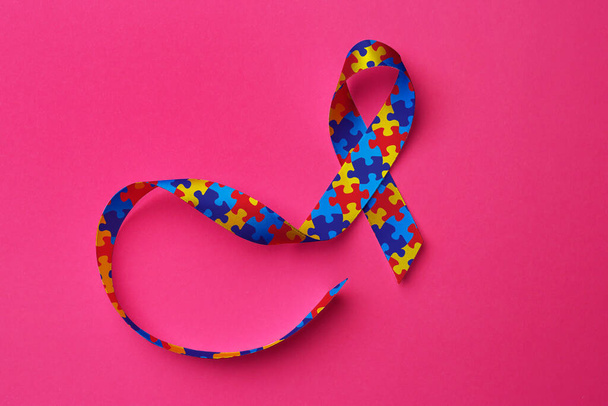 World Autism Awareness Day. Colorful puzzle ribbon on pink background, top view - Foto, Bild