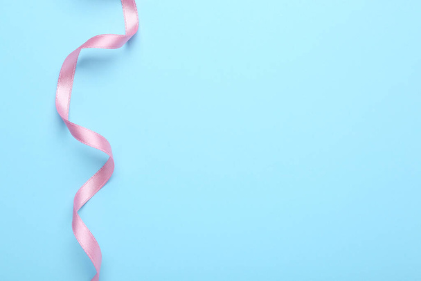 Beautiful pink ribbon on light background, top view. Space for text - 写真・画像