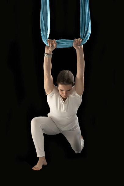 Aerial flying yoga exercises practice. Anti-gravity yoga pose. Fly yoga. Isolated on black background - Fotó, kép