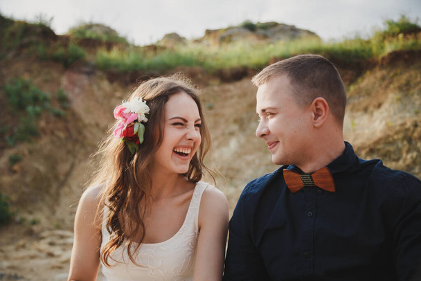 Outdoor beach wedding ceremony, close up of stylish happy smiling groom and bride are having fun and laughing looking at each other. - Foto, imagen