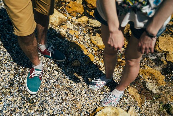 ODESSA, UKRAINE - MAY, 20 2015: Young hipster couple standing on the sand ant beach, dirty green red and white sneakers shoes top view. Sneakers shoes couple. - 写真・画像