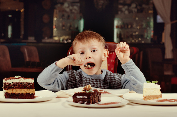 Μικρό αγόρι που τρώει μια φέτα κέικ με ενθουσιασμό και κέφι - Φωτογραφία, εικόνα