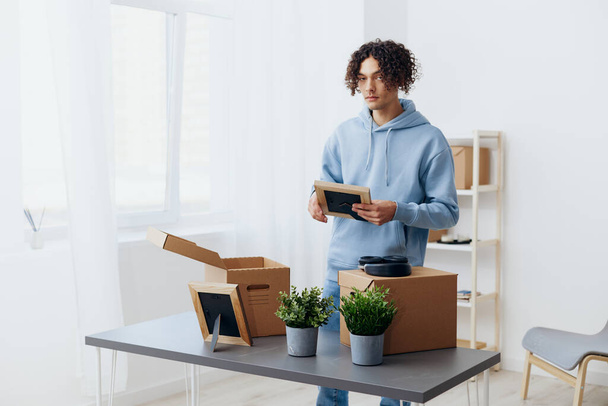 A young man unpacking things from boxes in the room Lifestyle. High quality photo - Photo, Image