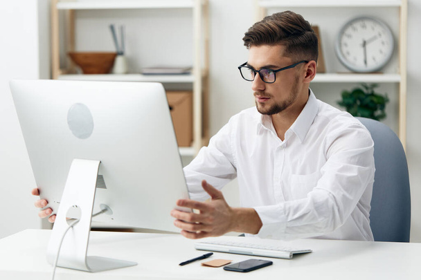 διευθυντής σε ένα λευκό πουκάμισο κάθεται σε μια εργασία υπολογιστή τεχνολογίες τεκμηρίωσης. Υψηλής ποιότητας φωτογραφία - Φωτογραφία, εικόνα
