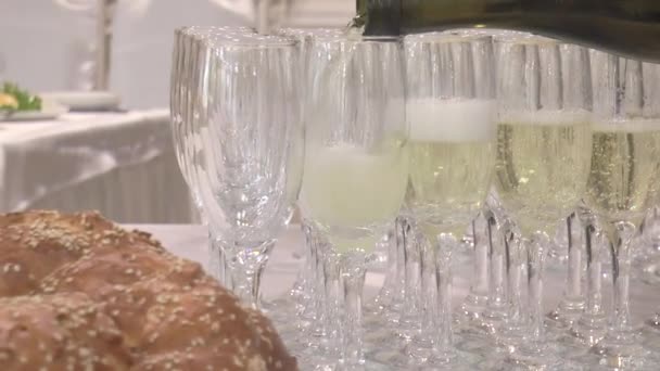 champagne glazen in een restaurant worden halfweg gevuld met champagne uit een fles. - Video