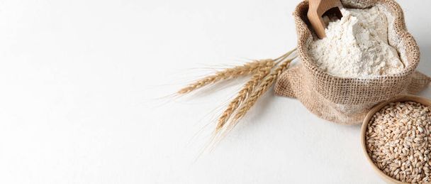 Taška s moukou a miska s pšeničnými zrny na bílém pozadí s prostorem pro text - Fotografie, Obrázek