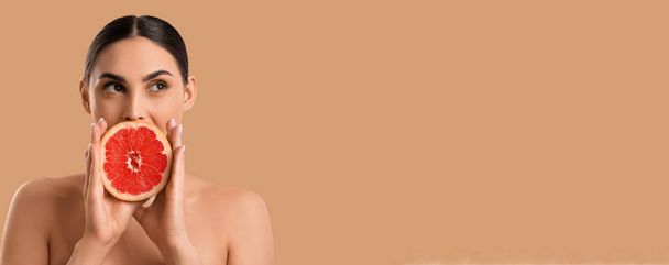 Naked young woman with fresh grapefruit on beige background with space for text - Photo, Image