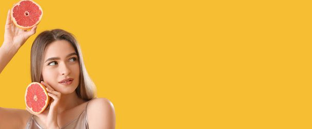 Beautiful young woman with grapefruit on yellow background with space for text - Foto, Imagem