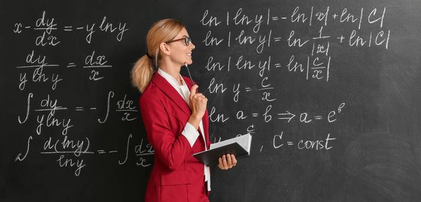 Beautiful maths teacher near blackboard in classroom - Foto, imagen