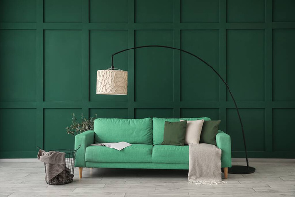 Bank, lamp en tafel bij groene muur in woonkamer - Foto, afbeelding