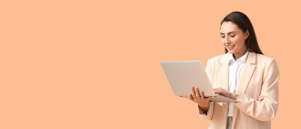 Pretty young businesswoman using laptop on beige background with space for text - 写真・画像
