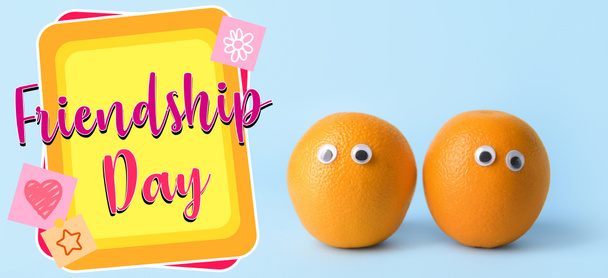 Śmieszne pomarańcze i tekst DZIEŃ FRIENDSHIP na jasnoniebieskim tle - Zdjęcie, obraz