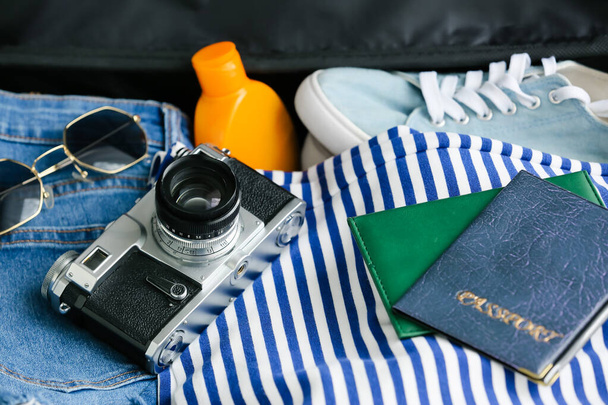 Reisepässe und Fotokamera auf Frauenkleidung im Koffer - Foto, Bild
