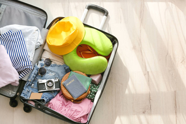 Nyitott bőrönd ruhákkal és különböző tartozékokkal könnyű fapadlón történő utazáshoz - Fotó, kép