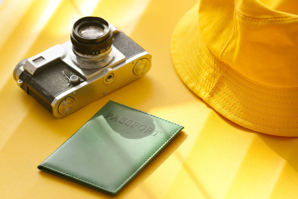 Διαβατήριο, καπέλο και φωτογραφική μηχανή σε κίτρινη βαλίτσα, κοντινό πλάνο - Φωτογραφία, εικόνα