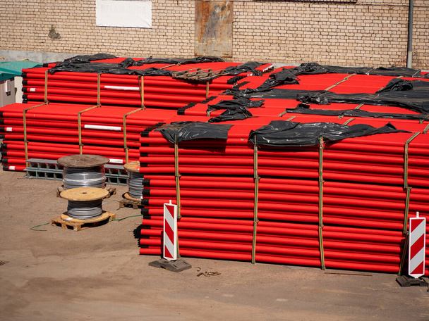 Een groot aantal rode rioolbuizen van hun pvc liggen in grote palen, het concept van reparatie, pijpvervanging, magazijn, tekort - Foto, afbeelding